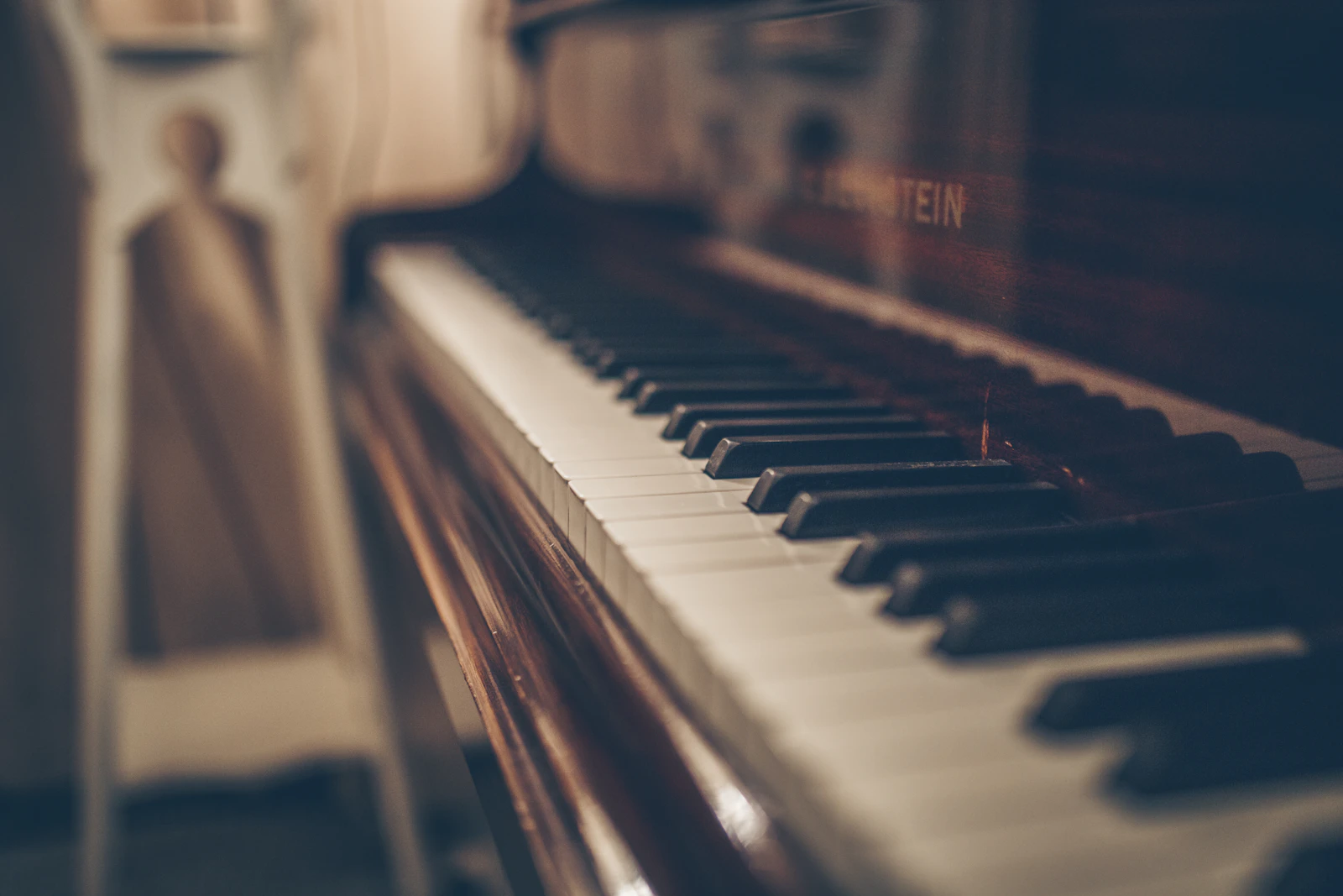 Warm light falling across the keys of a wooden piano